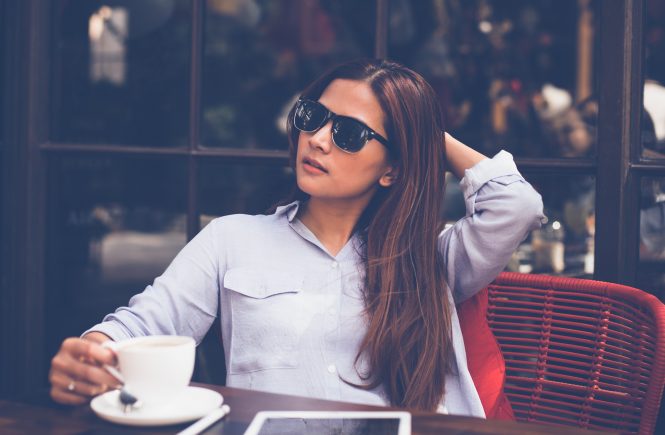 Frau draußen, mit Sonnenbrille, Kaffe und iPad
